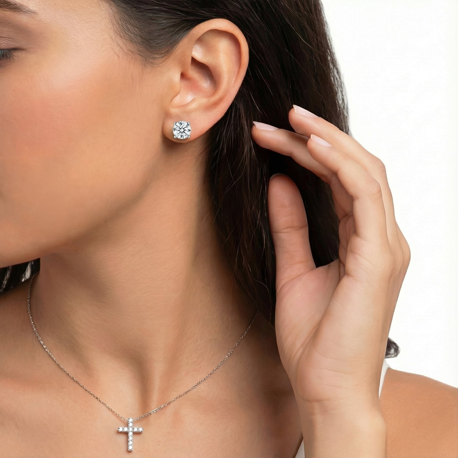 Woman wearing diamond earrings and a necklace on a white background